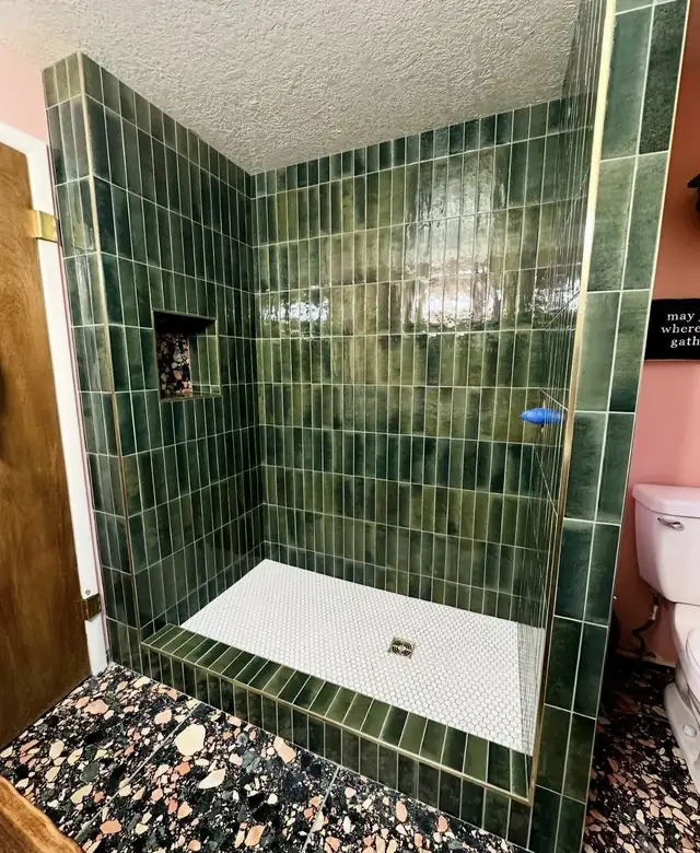 Shower with glossy green vertical tile, white penny tile floor and a terrazzo bathroom floor