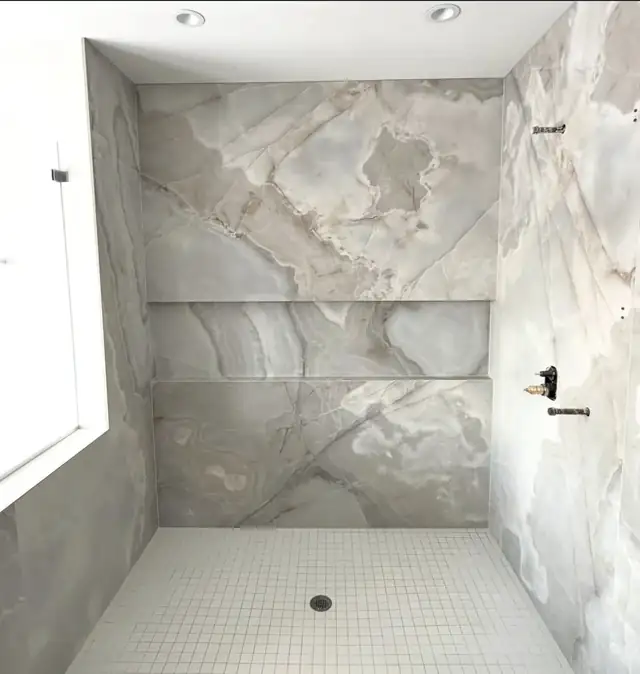 Light onyx-look porcelain shower with recessed shelf and white mosaic shower floor
