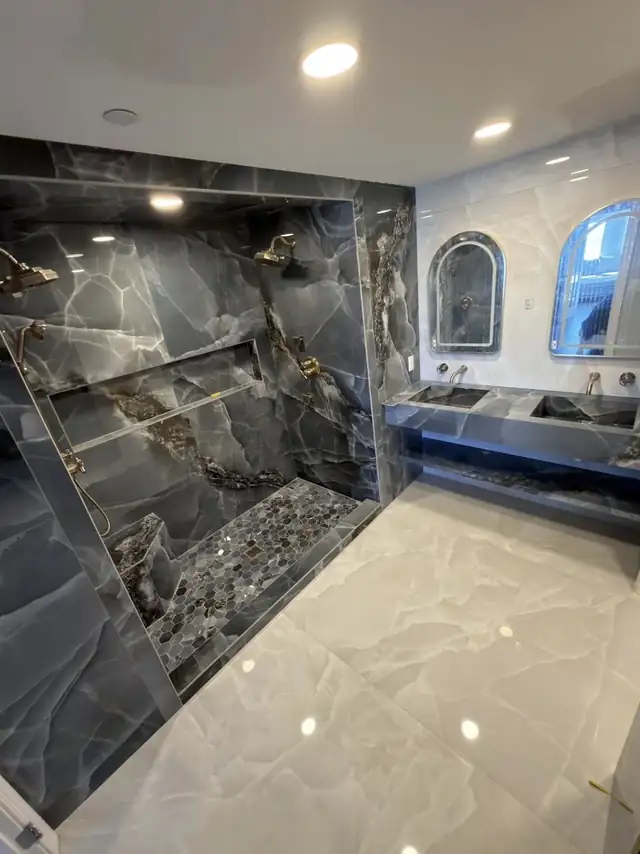Master bathroom with dark onyx-look porcelain shower walls, pebble shower floor and a floating double vanity with arched mirrors
