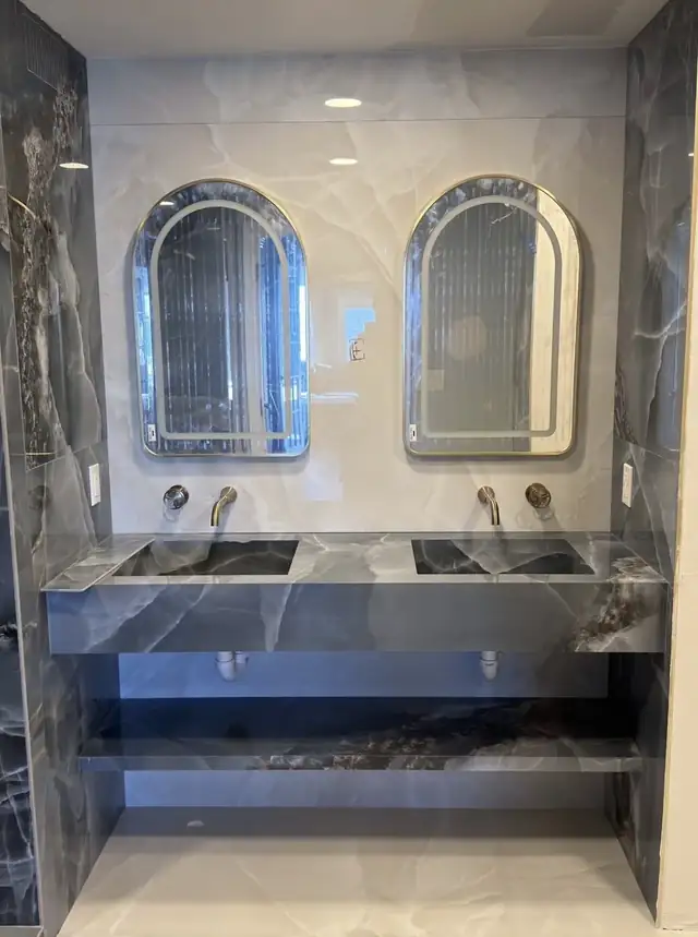 Floating double vanity wrapped in onyx-look porcelain with wall-mounted faucets and arched mirrors
