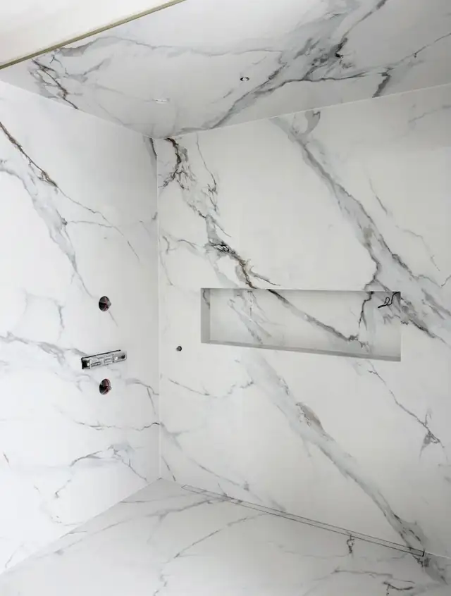 White marble-look large-format porcelain shower walls with a long recessed niche before glass install